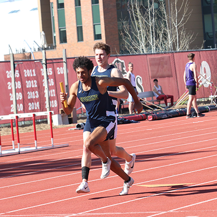 Track and field men passing the baton in running relay 