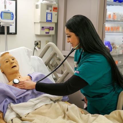 Nursing student uses stethescope with mannequin