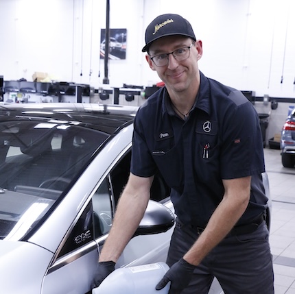 Peter Nelson adds washer fluid to a Mercedes EV