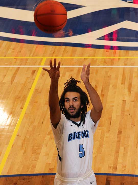Men's basketball player in mid shooting for the hoop