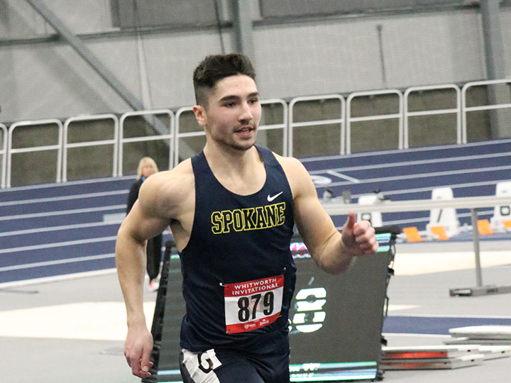 Men's track and field teammate running on the indoor track at the Spokane Podium