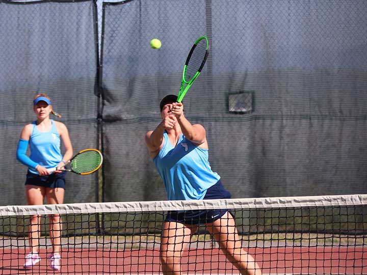 Women's tennis doubles player preparing to return the ball over the net