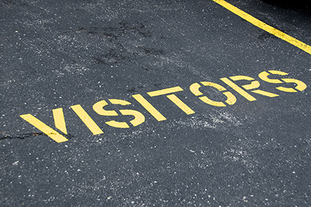 the word visitors painted on the asphalt for aparking space
